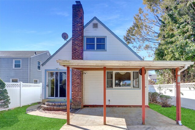 back of property with a lawn, a fenced backyard, brick siding, a chimney, and a patio area