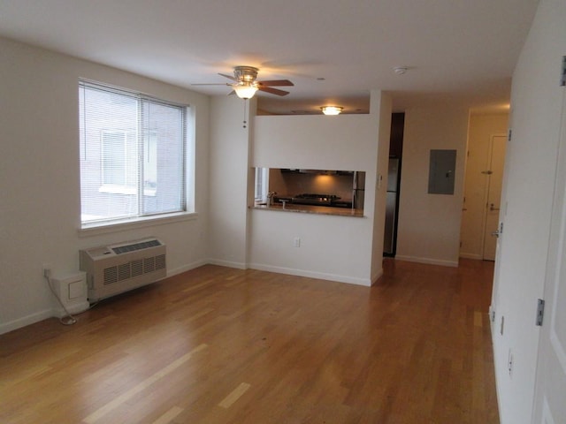 unfurnished living room featuring baseboards, electric panel, light wood finished floors, and a wall mounted AC