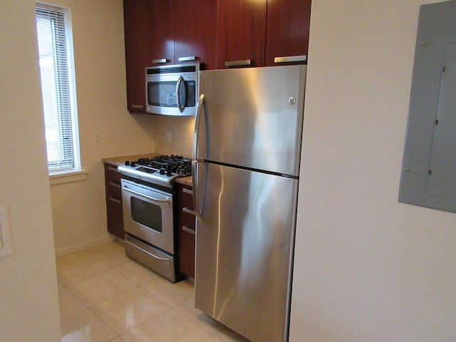 kitchen with stainless steel appliances, electric panel, baseboards, and light tile patterned flooring