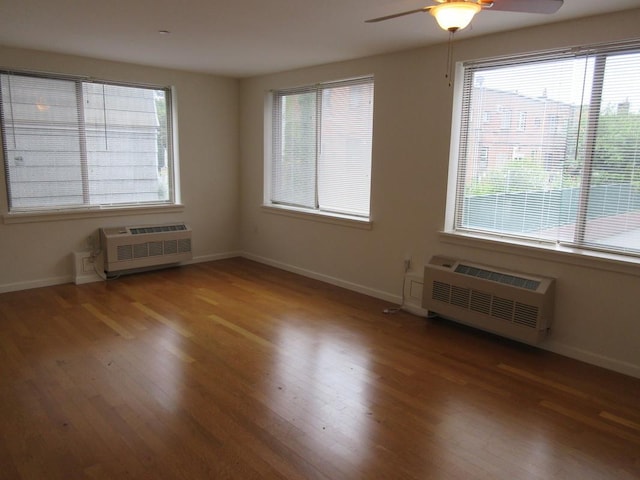 empty room featuring an AC wall unit, baseboards, and wood finished floors