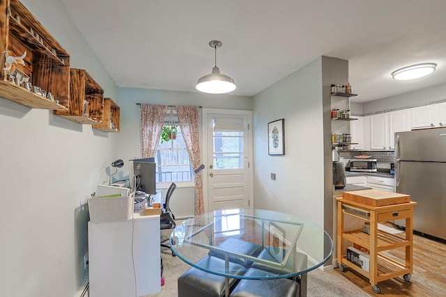 dining room featuring light wood finished floors and baseboards