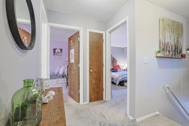 hallway with carpet, baseboards, and an upstairs landing