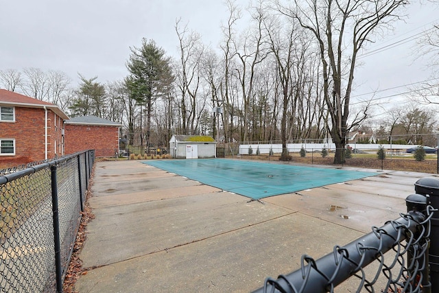 community pool with a patio, an outdoor structure, and fence