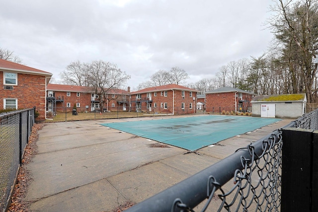 community pool with a patio area, fence, and a residential view