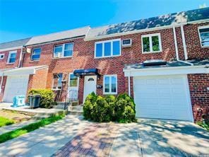 multi unit property featuring driveway, brick siding, and an attached garage