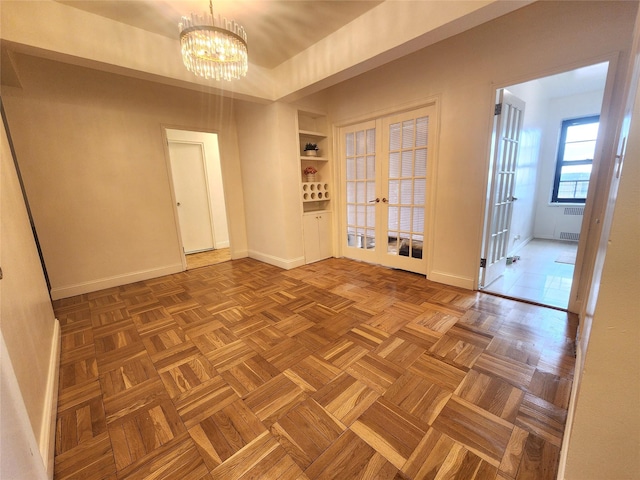 spare room with built in features, french doors, a notable chandelier, and baseboards