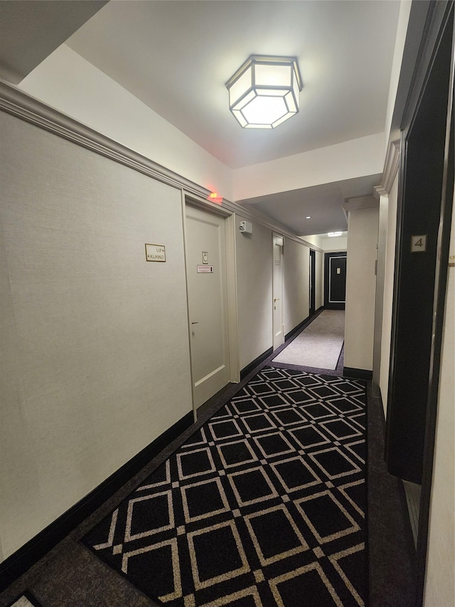 corridor featuring dark colored carpet and baseboards