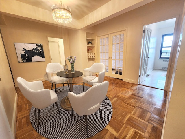 dining room with baseboards, built in features, radiator heating unit, french doors, and a notable chandelier