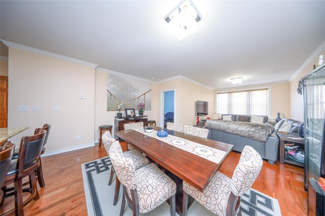 dining space with baseboards, ornamental molding, and light wood finished floors