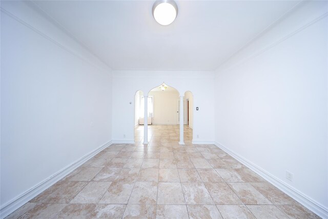 spare room with arched walkways, baseboards, and light tile patterned flooring