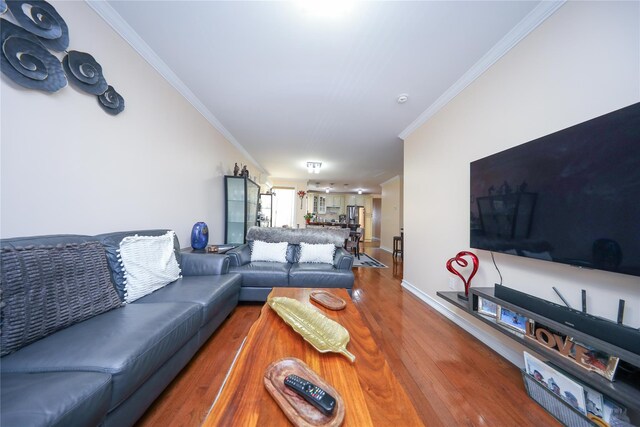 living area featuring crown molding, baseboards, and wood finished floors