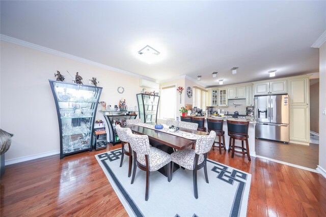 dining area with ornamental molding, a wall mounted air conditioner, and hardwood / wood-style floors