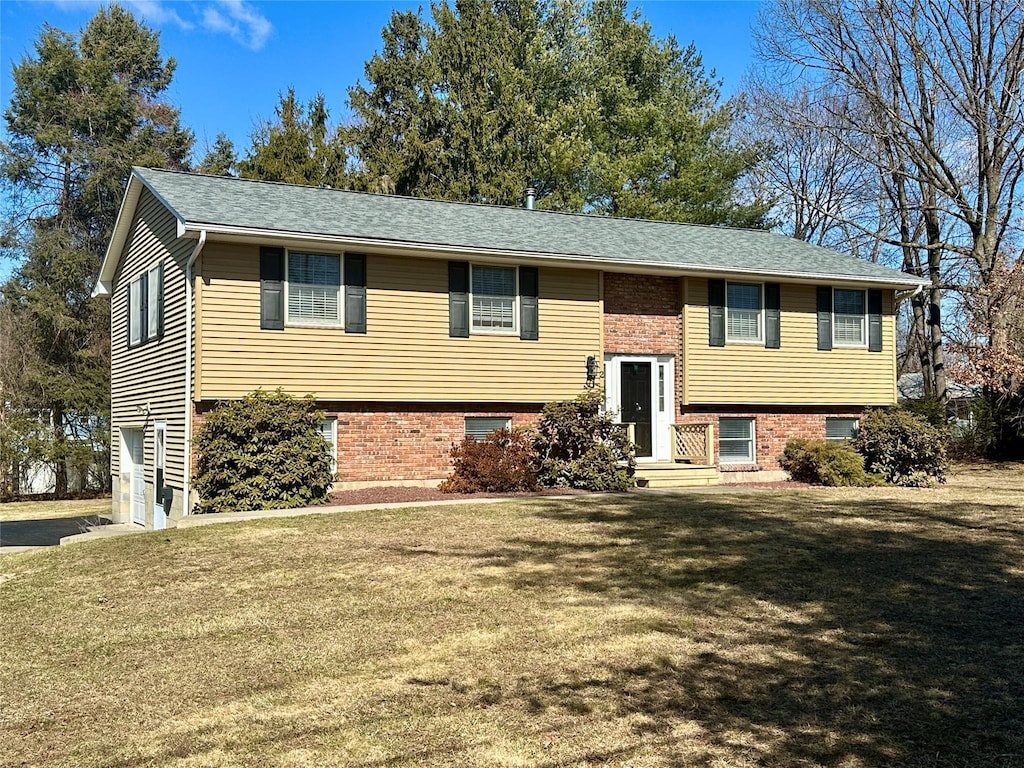 raised ranch with brick siding and a front yard