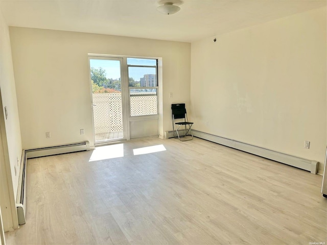 unfurnished room with baseboard heating and wood finished floors