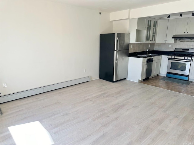 kitchen featuring decorative backsplash, appliances with stainless steel finishes, baseboard heating, under cabinet range hood, and a sink