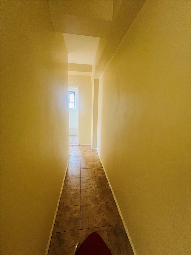 corridor with baseboards and dark tile patterned flooring