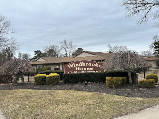 community / neighborhood sign featuring fence and a lawn