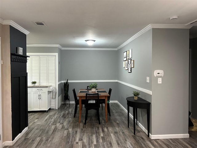 dining area featuring dark wood-style floors, visible vents, baseboards, and crown molding