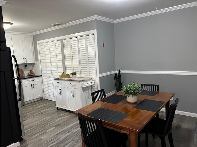 dining room with baseboards, visible vents, ornamental molding, and wood finished floors