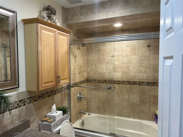 bathroom with tasteful backsplash, visible vents, and bath / shower combo with glass door