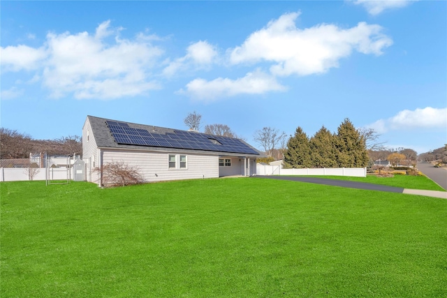 back of house featuring solar panels, a gate, a lawn, and a fenced backyard