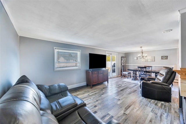 living room with an inviting chandelier, baseboards, light wood finished floors, and ornamental molding