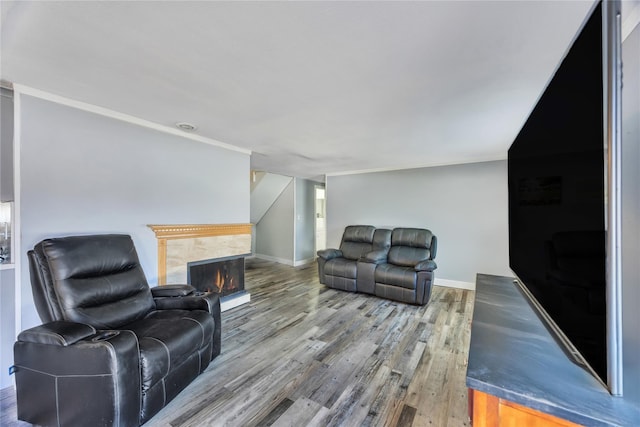 living area with wood finished floors, crown molding, a fireplace, and baseboards