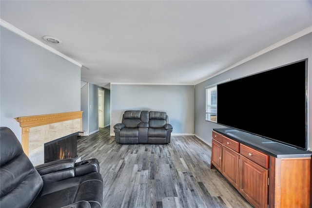 living room with baseboards, light wood-style flooring, a high end fireplace, and ornamental molding