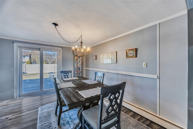 dining room featuring baseboard heating, an inviting chandelier, wood finished floors, and ornamental molding