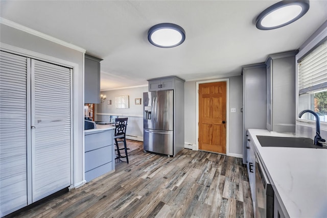 kitchen featuring gray cabinetry, a sink, dark wood finished floors, appliances with stainless steel finishes, and light countertops