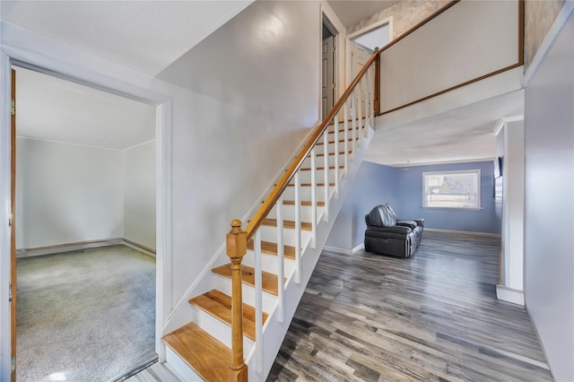 staircase with a high ceiling, wood finished floors, and baseboards