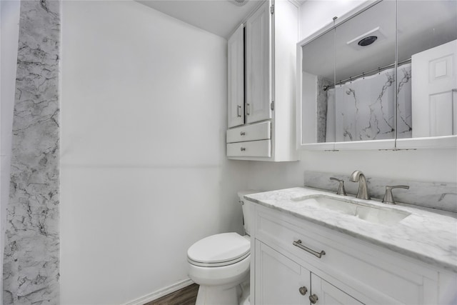 bathroom featuring curtained shower, toilet, vanity, and wood finished floors