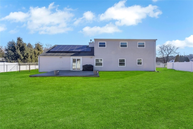 back of house with a yard, solar panels, a fenced backyard, and a patio area