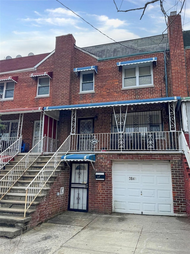 view of property with stairs, brick siding, an attached garage, and driveway