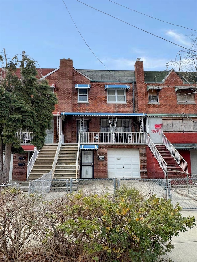 view of property featuring brick siding, a fenced front yard, stairs, a garage, and driveway