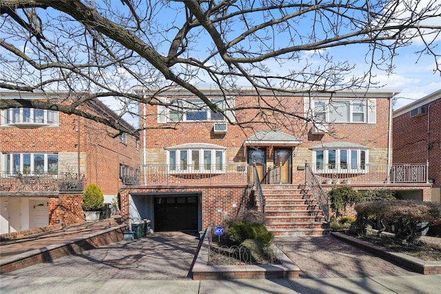 view of front of house with brick siding, driveway, an attached garage, and stairs