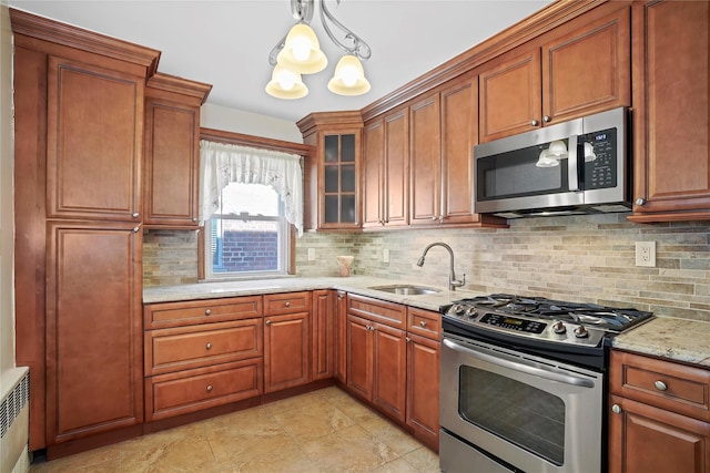 kitchen with stainless steel appliances, brown cabinets, a sink, and backsplash