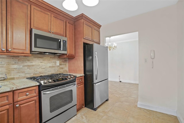 kitchen featuring tasteful backsplash, an inviting chandelier, appliances with stainless steel finishes, brown cabinetry, and light stone countertops