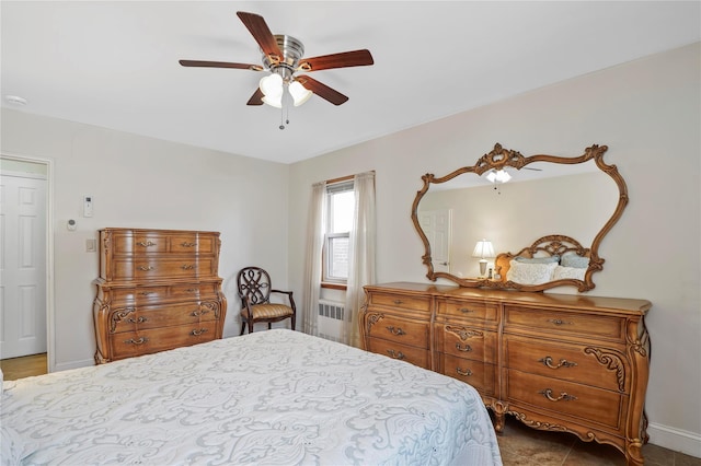 bedroom featuring a ceiling fan, radiator heating unit, and baseboards