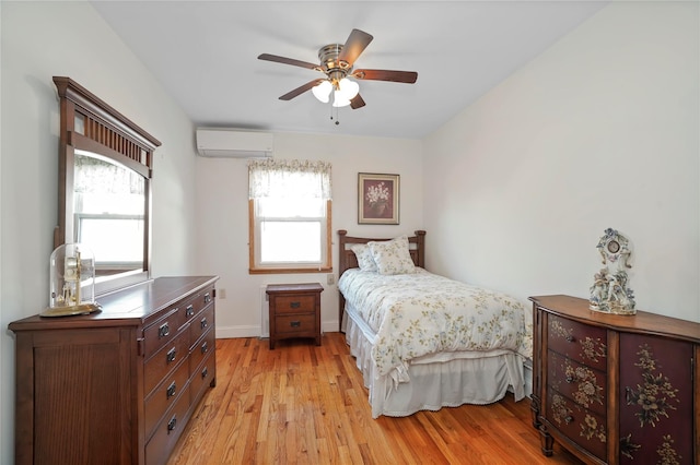 bedroom featuring an AC wall unit, multiple windows, light wood-style flooring, and baseboards