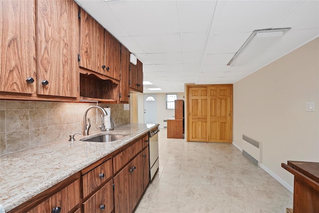 kitchen with tasteful backsplash, baseboards, dishwasher, light stone countertops, and a sink