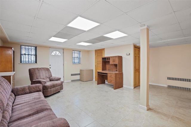 living room with radiator heating unit, a paneled ceiling, and baseboards