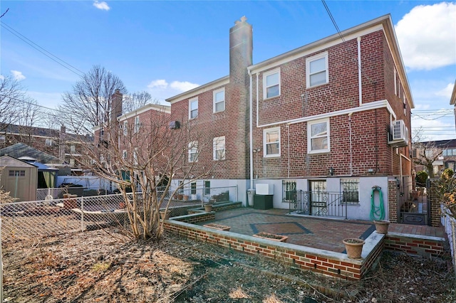 back of property with brick siding, fence, and a chimney