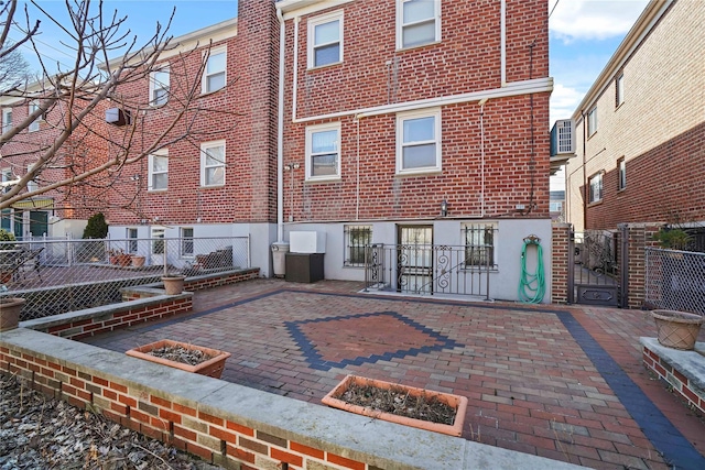 back of house with a patio area, fence, and brick siding