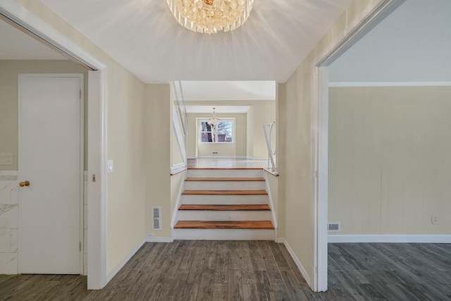 stairs with visible vents, a notable chandelier, and wood finished floors