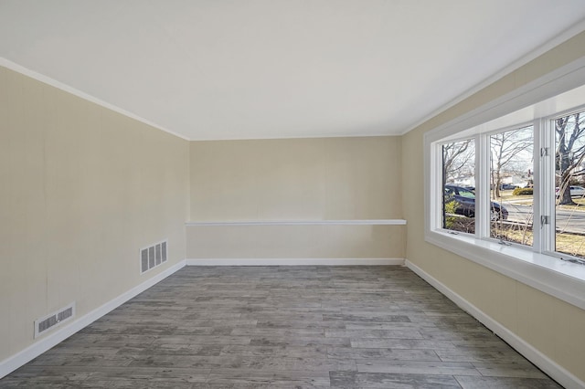 spare room with wood finished floors, visible vents, and baseboards