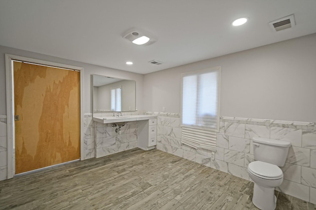 bathroom with toilet, a wainscoted wall, visible vents, and wood finished floors