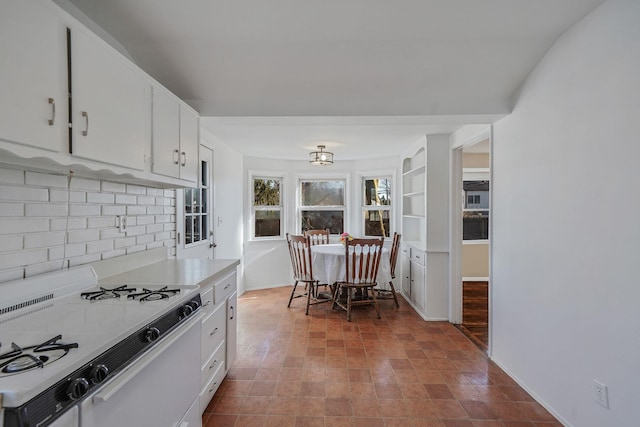 kitchen with light countertops, decorative backsplash, white cabinetry, white range with gas cooktop, and baseboards