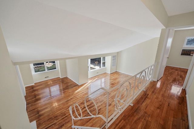 unfurnished living room featuring lofted ceiling, plenty of natural light, hardwood / wood-style flooring, and baseboards