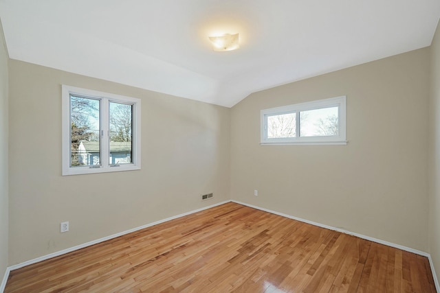 unfurnished room featuring light wood-type flooring, baseboards, visible vents, and lofted ceiling